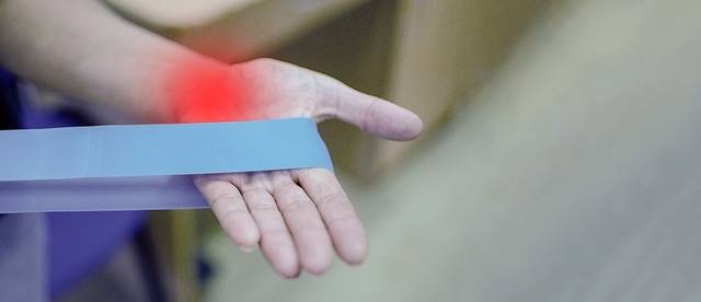 someone working on carpal tunnel exercises with a blue band showing a red area representing pain in the wrist